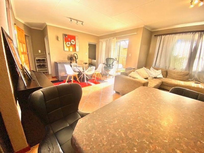 Spacious open-plan living and dining area featuring tiled flooring, track lighting, and direct access to the outdoor patio through a sliding glass door.