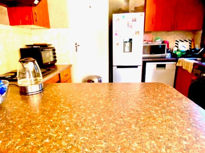 A functional kitchen featuring laminate countertops, built-in cabinetry, and a tiled backsplash, providing a practical workspace for daily meal preparation.
