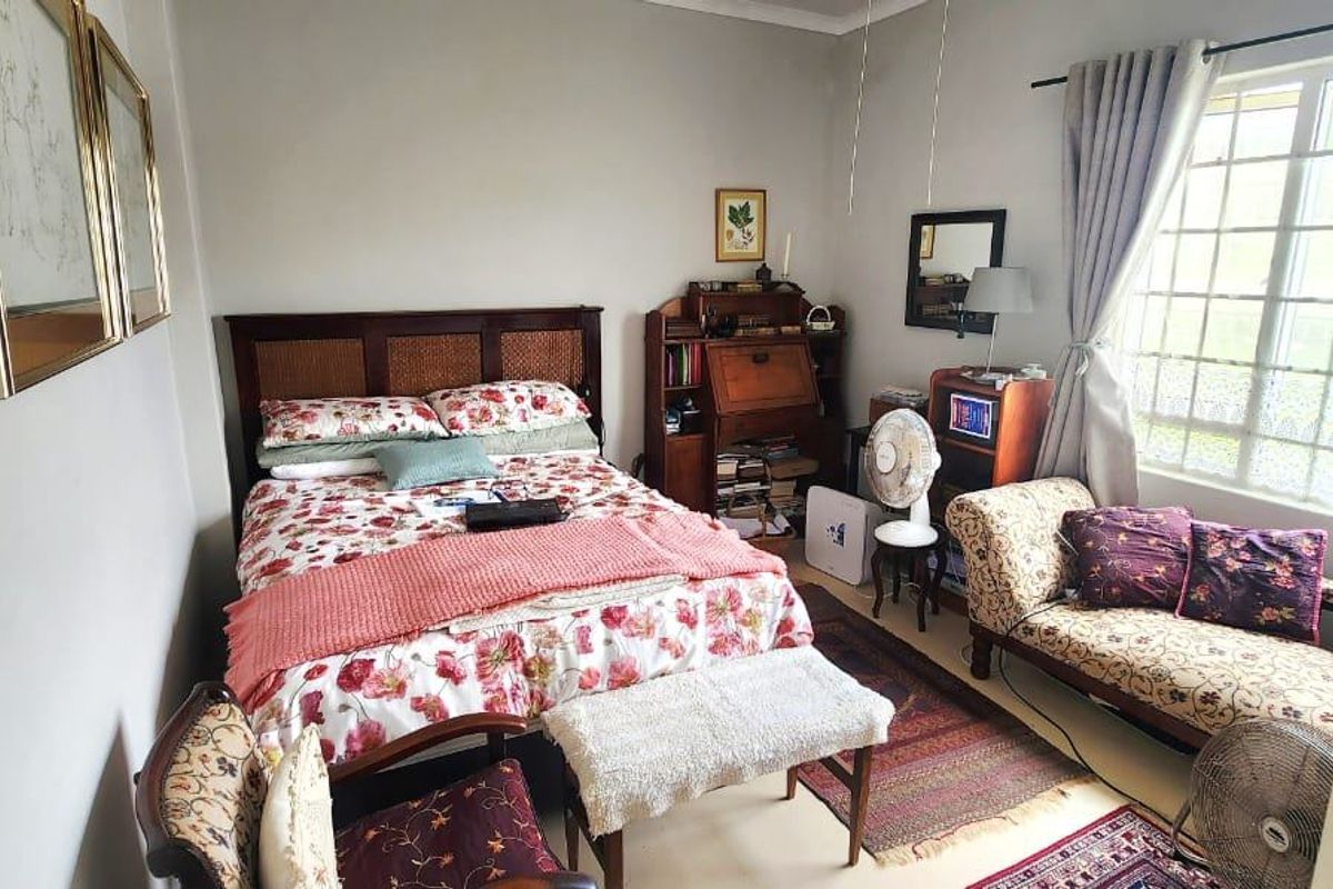 A cozy bedroom featuring a window with security bars and classic cove cornicing, offering a functional and well-lit living space.
