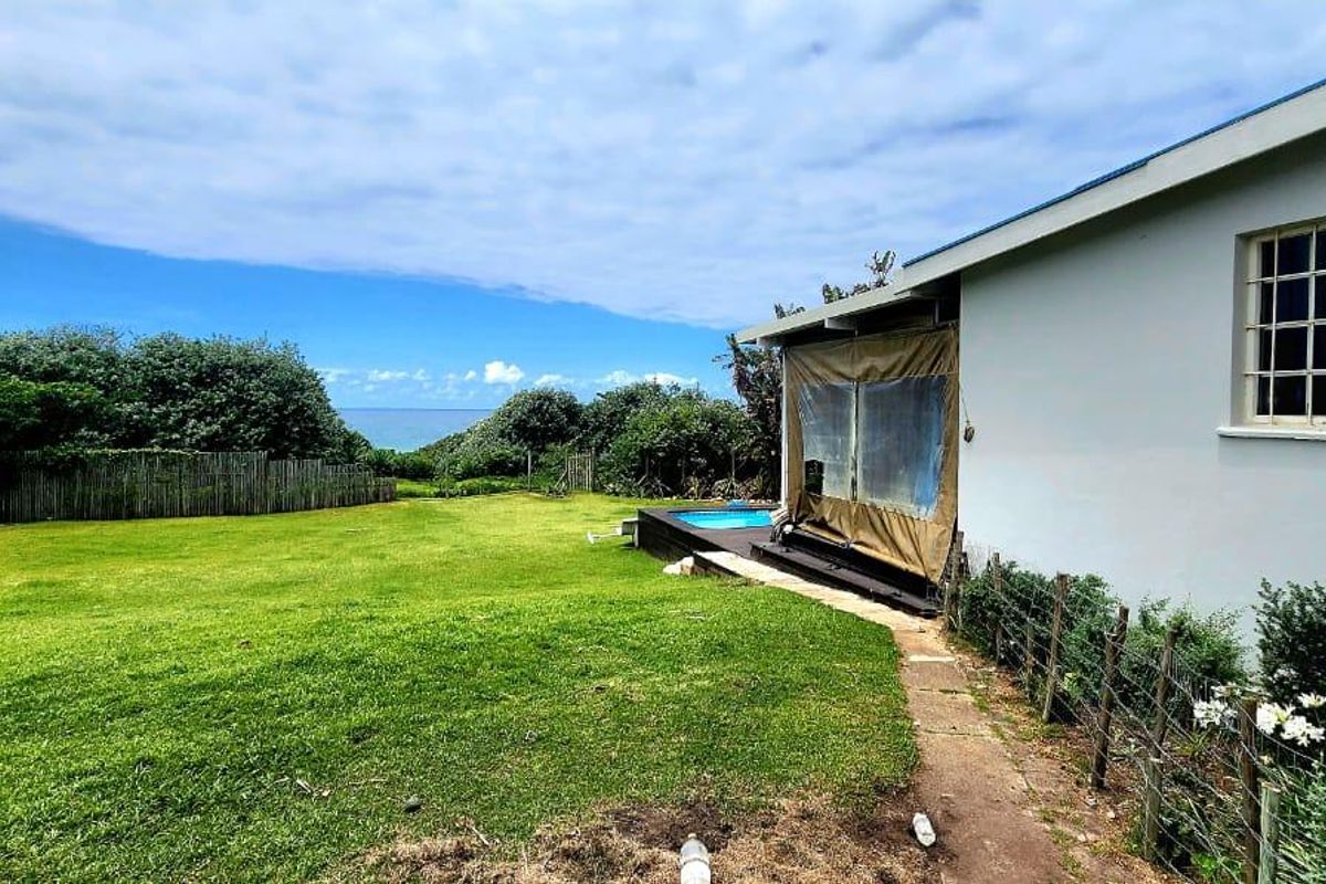 Rear exterior view featuring a lawn, a small swimming pool, and a covered patio area with security bars on the windows.