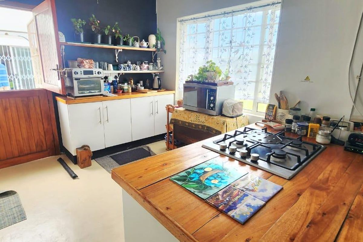 A functional kitchen featuring a wooden countertop, gas hob, and built-in cabinetry with open shelving, providing a practical workspace with direct outdoor access.