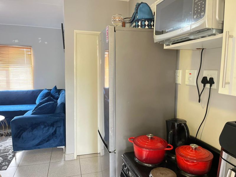 Open-plan kitchen and living area featuring tiled flooring, built-in microwave, and electric stove, with direct access to the adjacent living space.