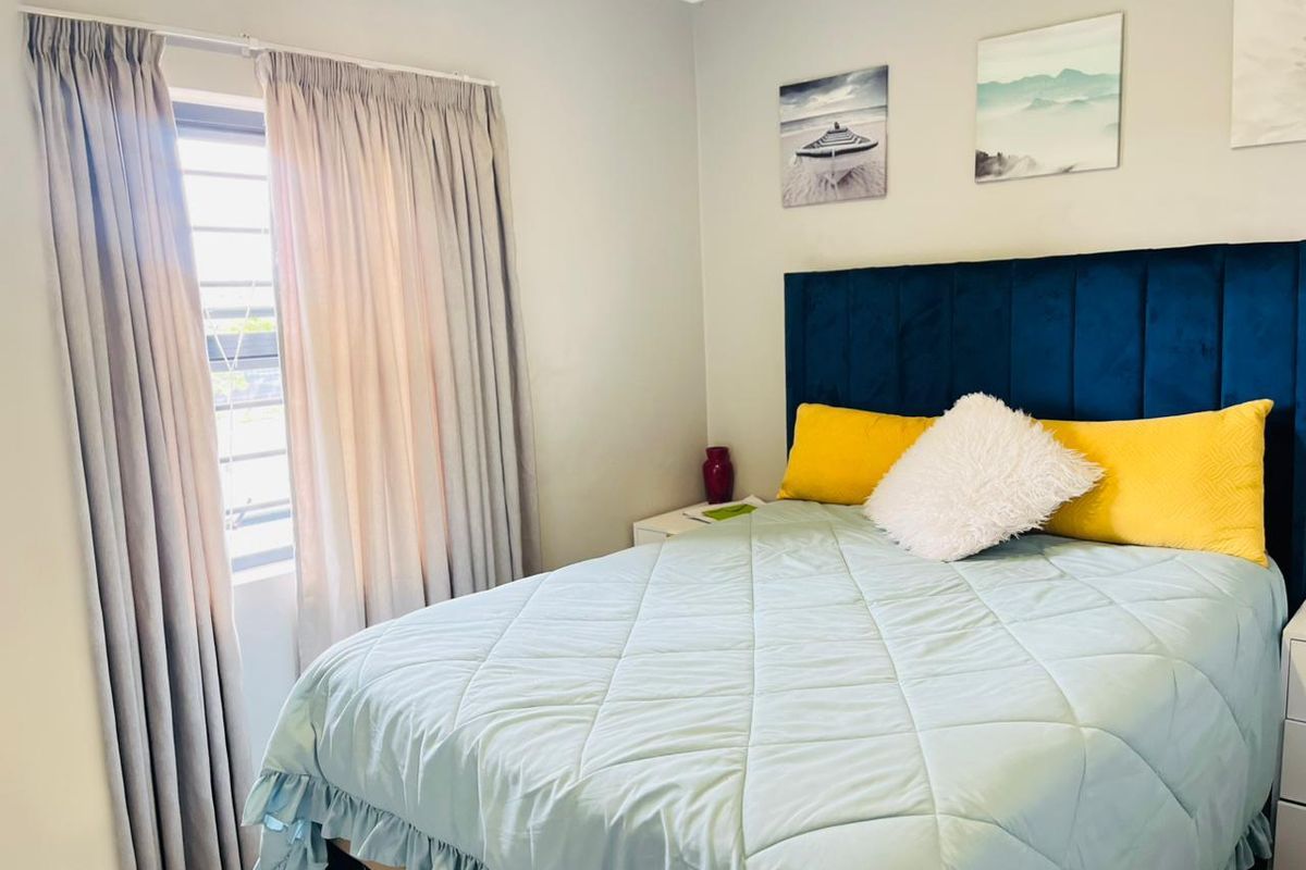 A well-maintained bedroom featuring neutral wall finishes, a window with security bars, and functional curtain tracks.