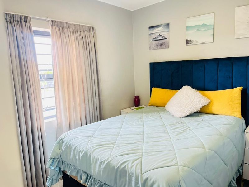 A well-maintained bedroom featuring neutral wall finishes, a window with security bars, and functional curtain tracks.