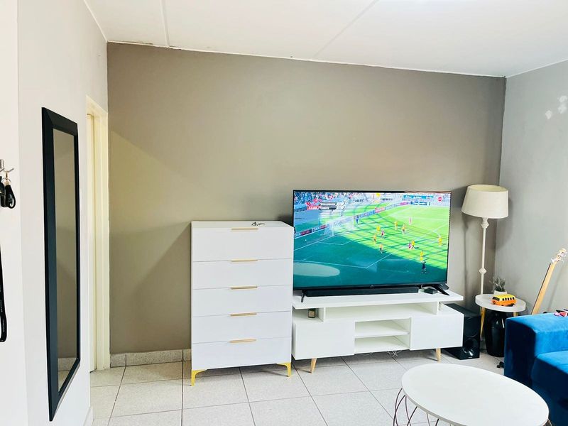 A living room area featuring neutral wall tones and tiled flooring, providing a functional space for relaxation and entertainment.