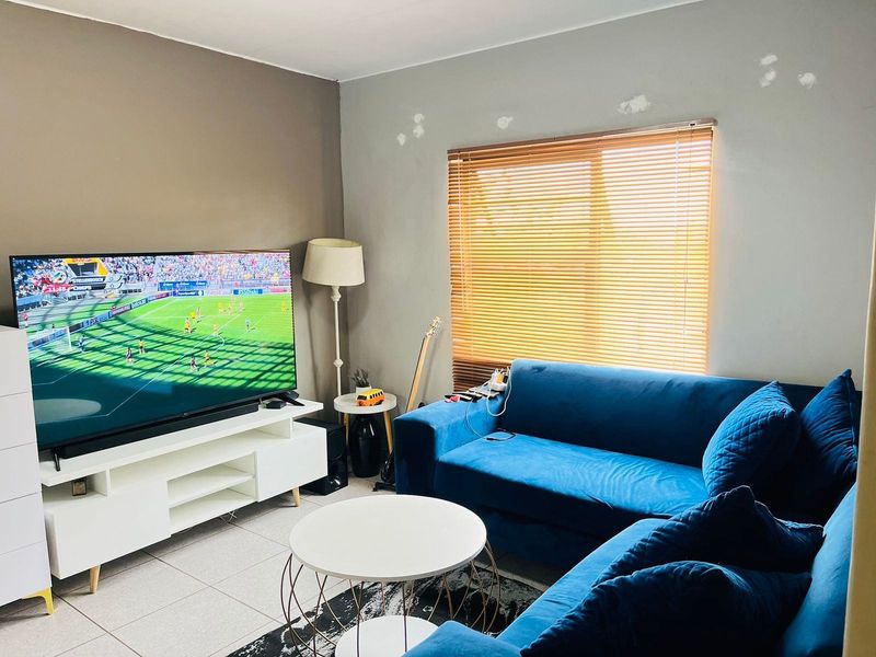 A living room featuring tiled flooring and venetian blinds, currently requiring minor wall repairs and repainting to improve the overall aesthetic.