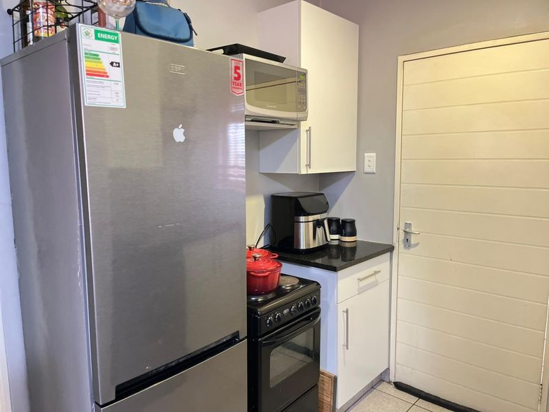 Compact kitchen area featuring white cabinetry, granite countertops, a freestanding stove, and built-in microwave, providing functional preparation space.