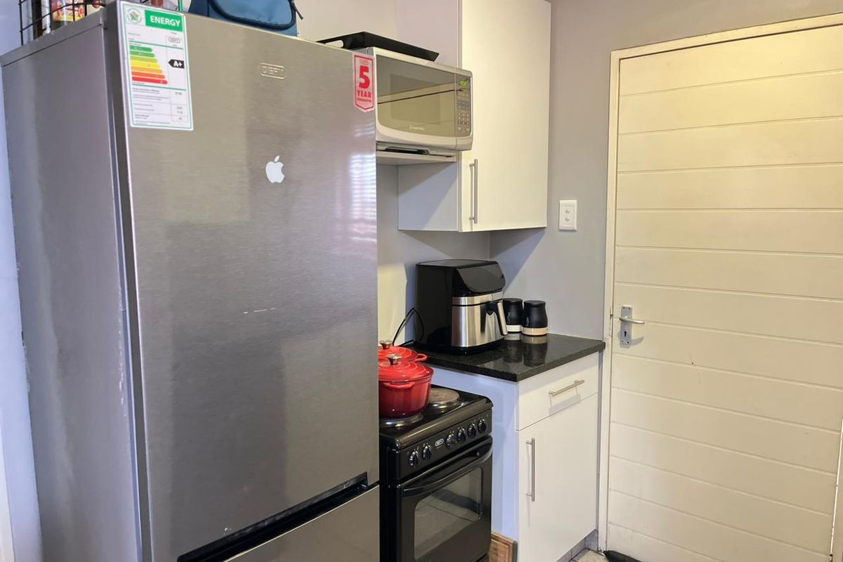 Compact kitchen area featuring white cabinetry, granite countertops, a freestanding stove, and built-in microwave, providing functional preparation space.