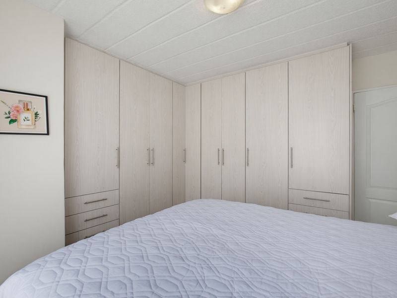 A well-maintained bedroom featuring extensive light-toned built-in cabinetry providing ample storage space.