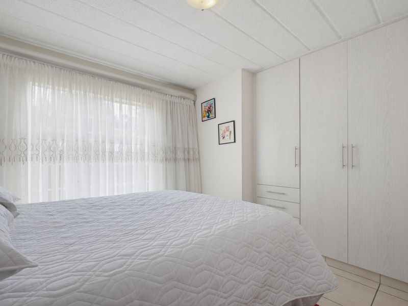 A well-maintained bedroom featuring built-in wardrobes, tiled flooring, and a textured ceiling, offering a clean and functional living space.
