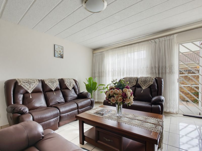 A comfortable living room featuring tiled flooring, a textured ceiling, and a sliding glass door providing access to the exterior.