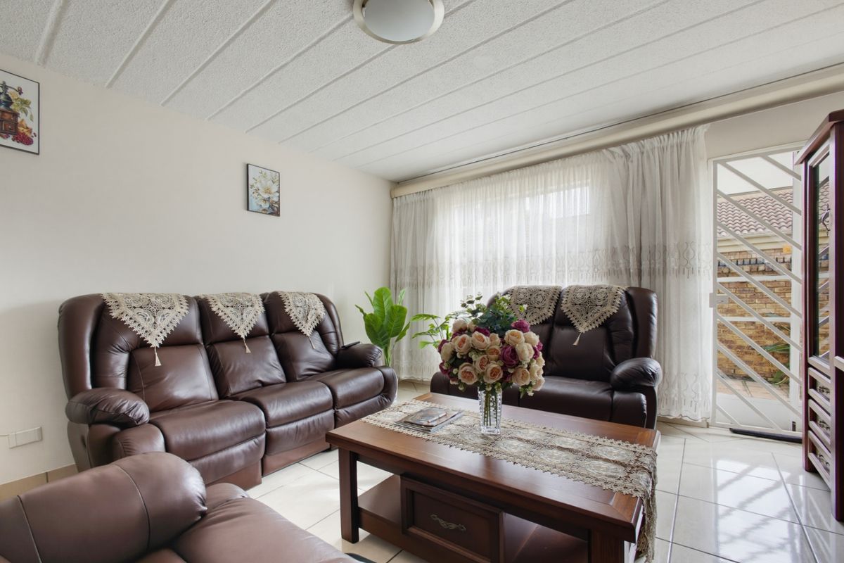 A comfortable living room featuring tiled flooring, a textured ceiling, and a sliding glass door providing access to the exterior.