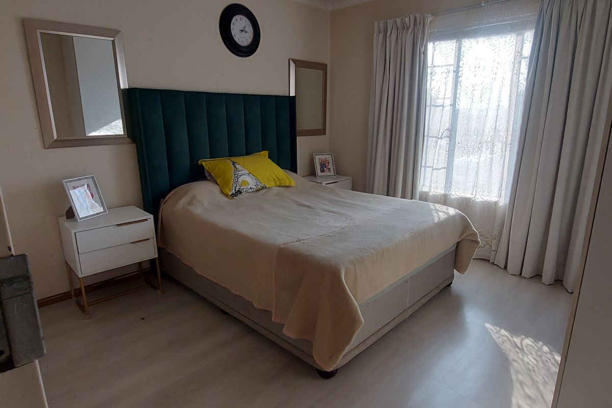 A well-lit bedroom featuring light-toned laminate flooring and neutral wall finishes, providing a comfortable and functional sleeping space.