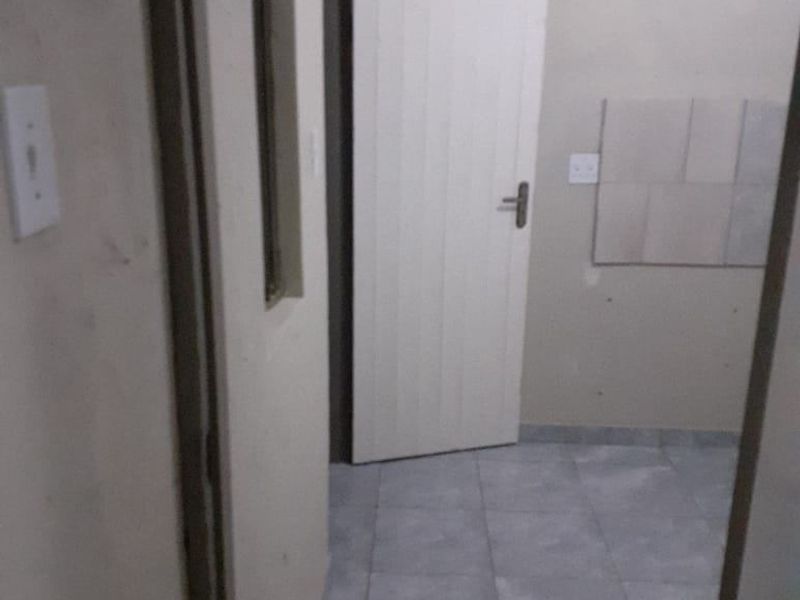 A vacant hallway featuring tiled flooring and neutral wall finishes, providing access to adjacent rooms within the apartment.