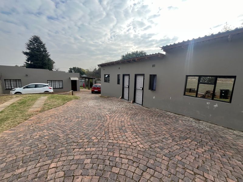 Exterior view of the property featuring a paved cobblestone driveway, secure entrance doors, and a well-maintained facade with tiled roofing.