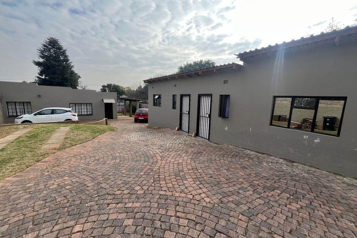 Exterior view of the property featuring a paved cobblestone driveway, secure entrance doors, and a well-maintained facade with tiled roofing.