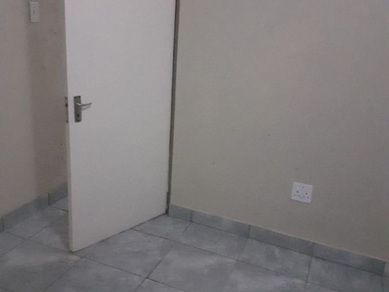 An empty bedroom featuring neutral wall paint and tiled flooring, providing a blank canvas for personalization.