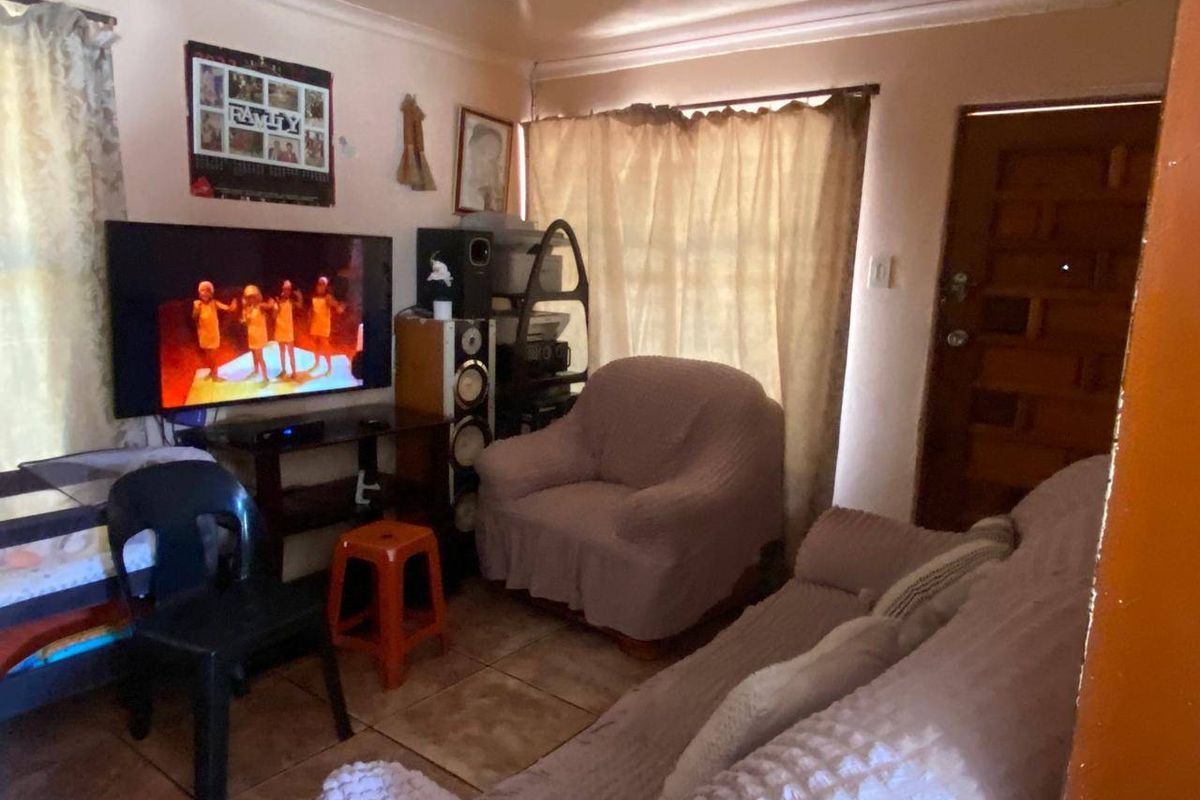 A compact living room featuring tiled flooring and a timber entrance door, providing a functional and lived-in space.