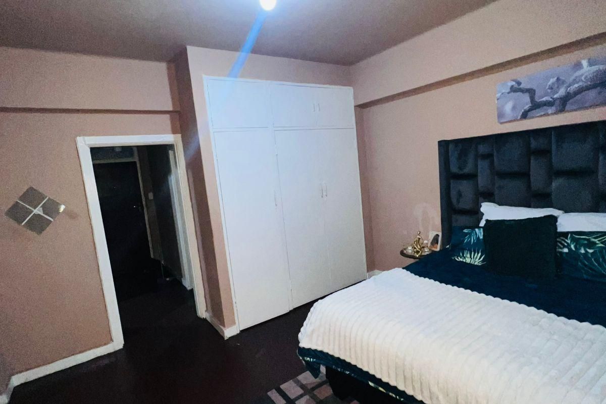 A bedroom featuring a built-in wardrobe and neutral wall finishes, providing a functional space with potential for modern updates.