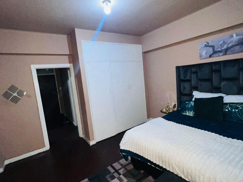 A bedroom featuring a built-in wardrobe and neutral wall finishes, providing a functional space with potential for modern updates.