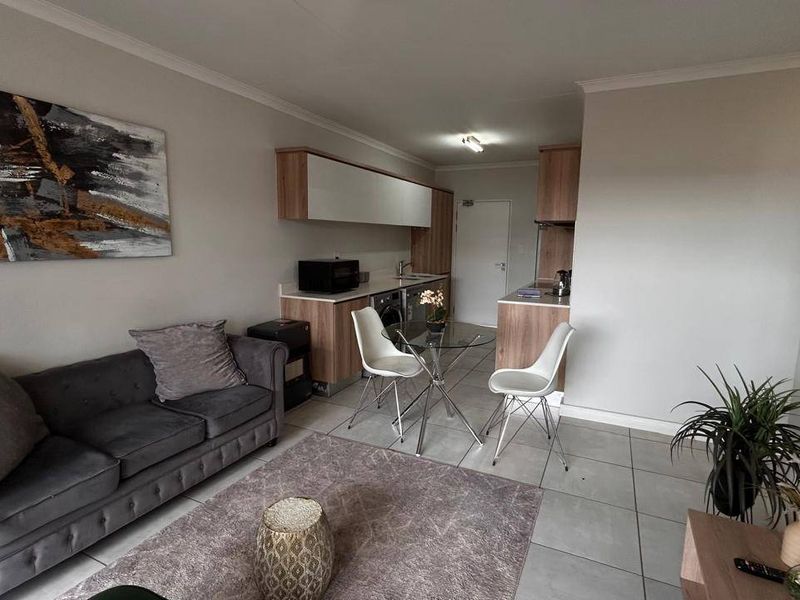 An open-plan living and kitchen area featuring modern cabinetry, tiled flooring, and a functional layout suitable for compact apartment living.