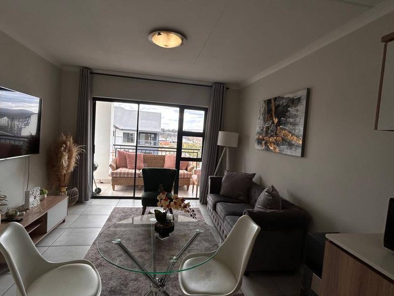 Open-plan living area featuring tiled flooring and a large sliding glass door providing access to the balcony.