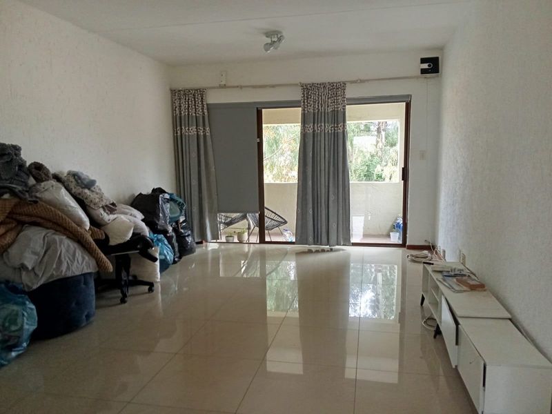 Spacious living area featuring large format floor tiles and a sliding glass door providing access to an outdoor balcony.