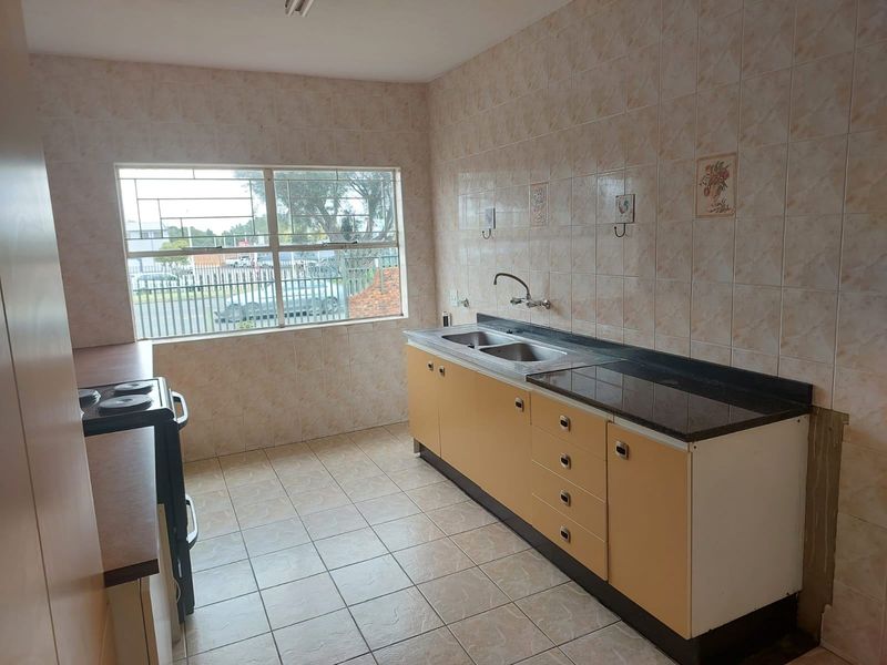A functional kitchen featuring tiled walls, built-in cabinetry, a double bowl sink, and ceramic floor tiles, offering a blank canvas for renovation.