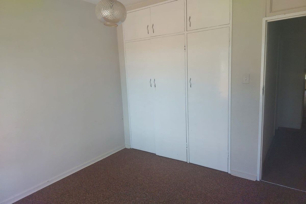 An empty bedroom featuring built-in cupboards and carpeted flooring, offering a blank canvas for potential updates and interior design improvements.