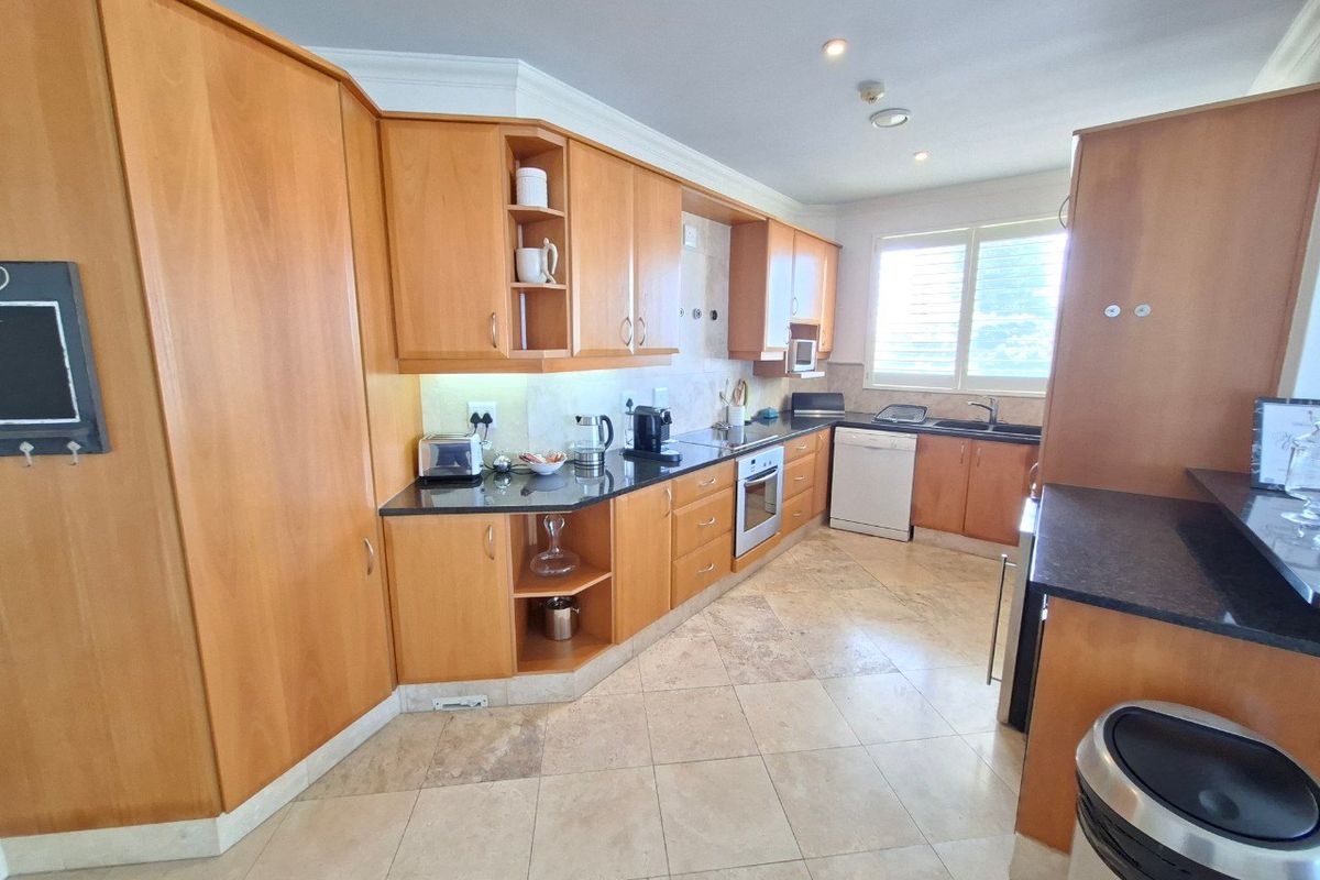 A functional kitchen featuring warm-toned wooden cabinetry, granite countertops, integrated oven, and tiled flooring, offering a classic layout with ample storage space.