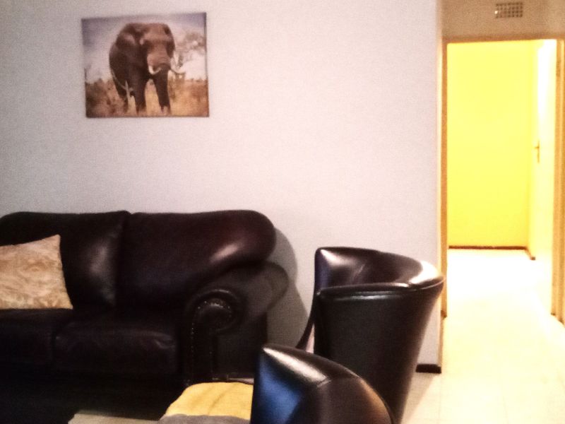 A living room area with tiled flooring and access to an adjacent hallway.