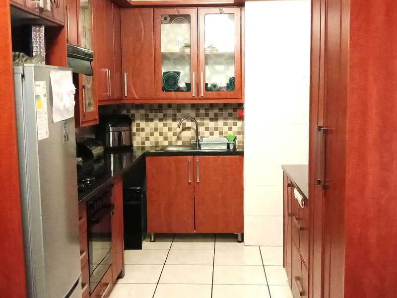 A functional kitchen featuring warm-toned wooden cabinetry, granite countertops, a tiled backsplash, and integrated appliances, offering a practical layout for daily use.