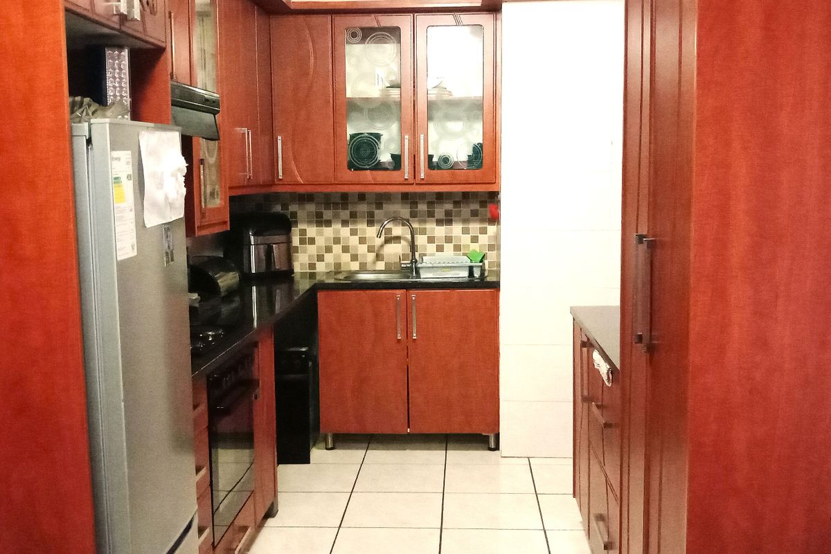 A functional kitchen featuring warm-toned wooden cabinetry, granite countertops, a tiled backsplash, and integrated appliances, offering a practical layout for daily use.