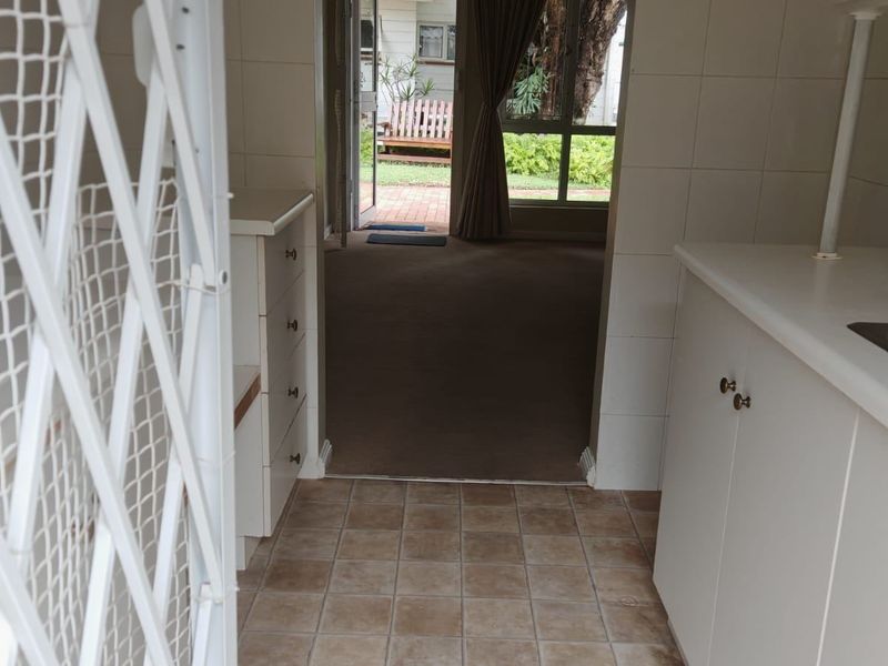 A functional scullery area featuring built-in cabinetry and tiled finishes, providing a direct transition to the living space and outdoor garden area.