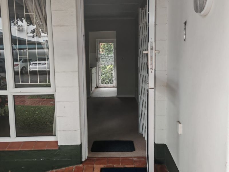 Entrance area featuring a brick-paved patio, security gate, and direct access into the home's interior hallway.