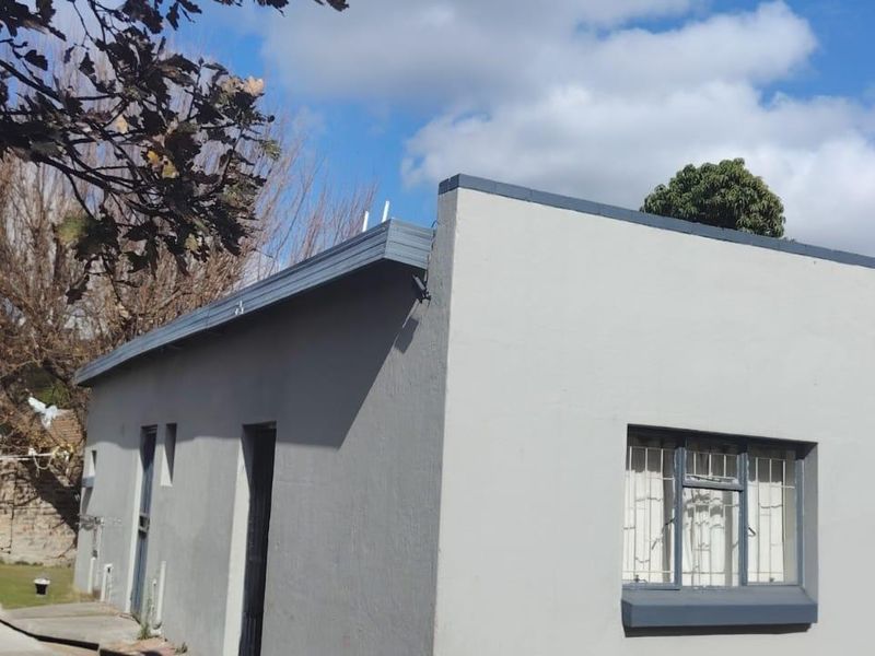 A view of the rear exterior of the house featuring a flat roof design, security bars on windows, and a concrete driveway.