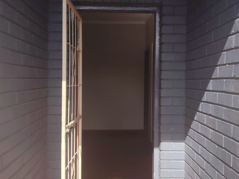A view of the property entrance featuring a painted brick facade and a metal security gate.
