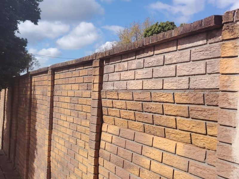A view of the property's brick boundary wall along the street frontage, showing signs of structural bowing in the masonry.