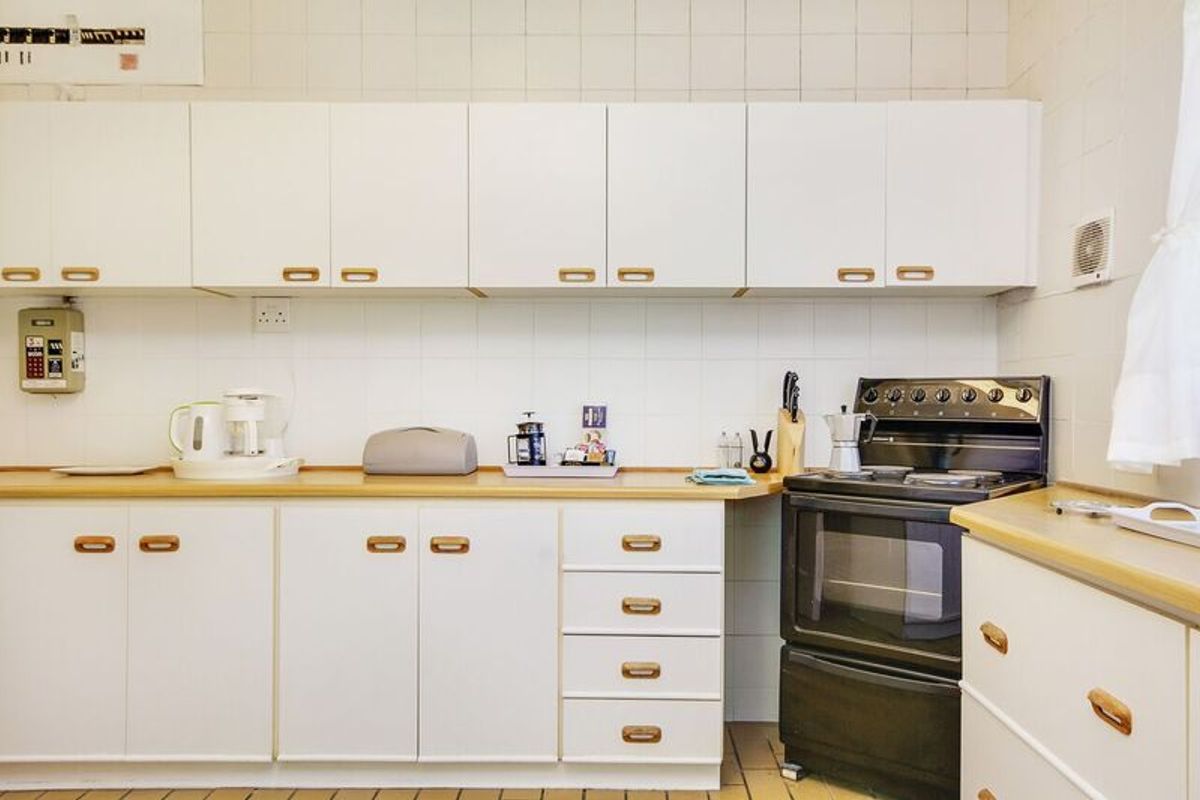 A functional kitchen featuring white cabinetry, laminate countertops, tiled backsplash, and a freestanding oven, offering a clean and practical workspace.