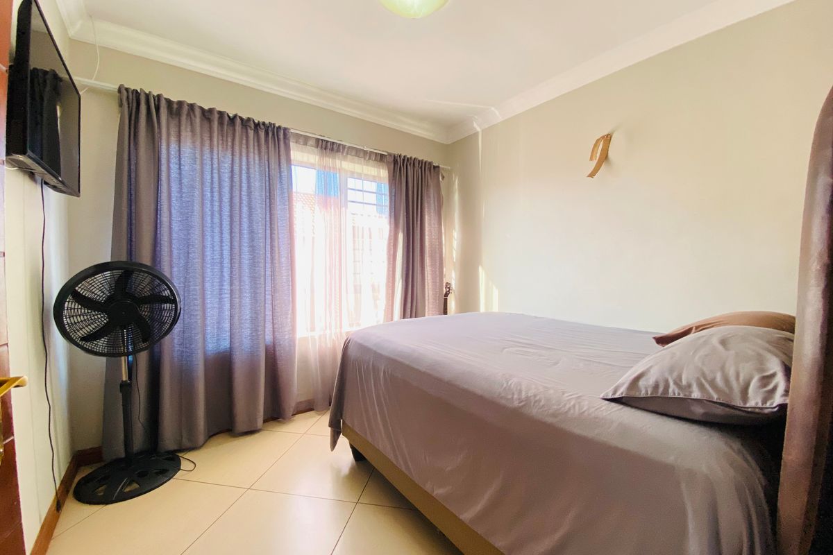 A functional bedroom featuring tiled flooring, neutral wall finishes, and a ceiling-mounted light fixture.