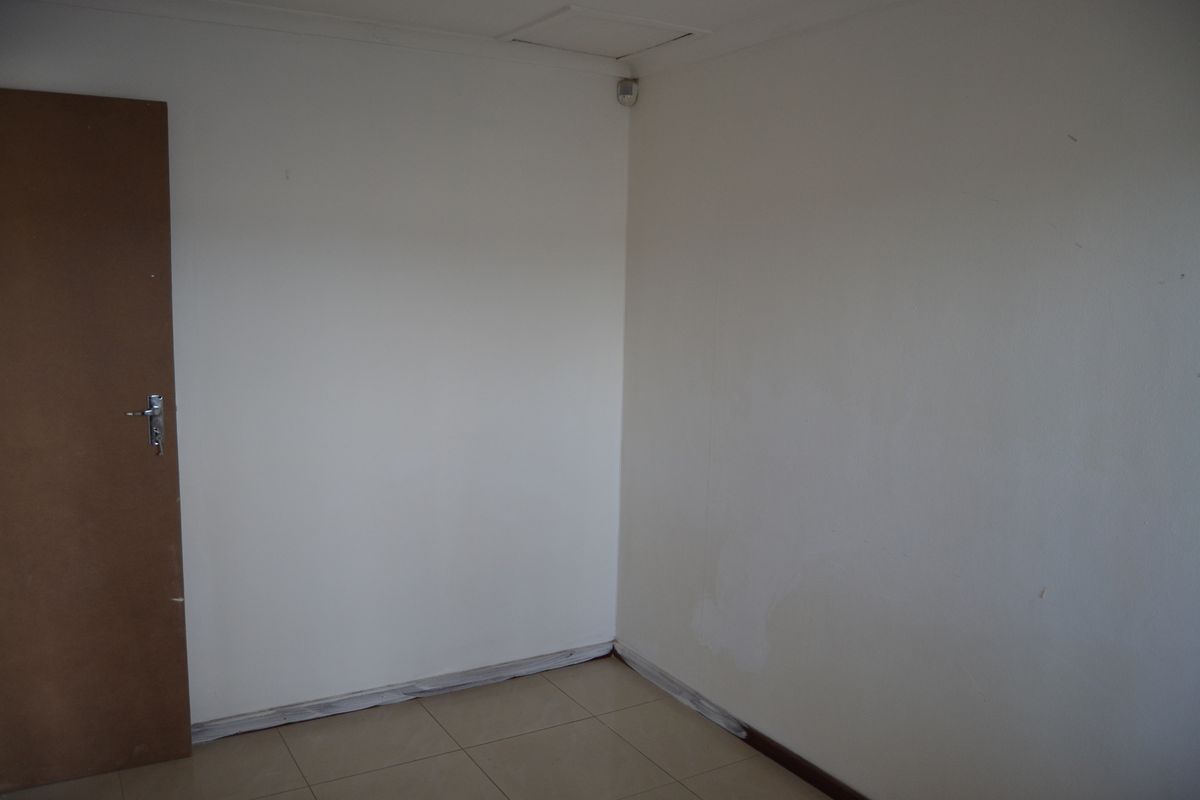 An empty bedroom featuring tiled flooring and neutral walls, requiring minor cosmetic attention to the skirting boards and wall finishes.