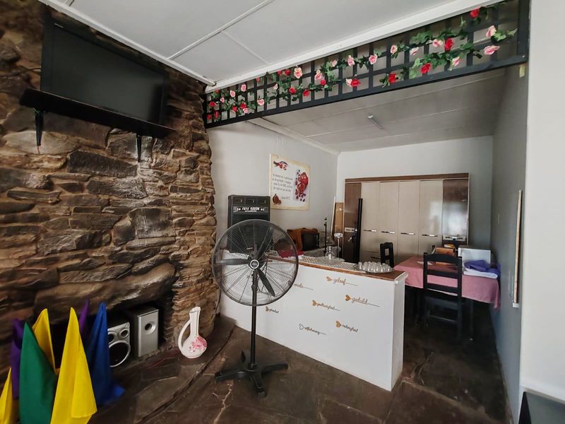 Living area featuring a prominent stone fireplace, stone flooring, and built-in cabinetry, offering a rustic aesthetic with potential for modernization.