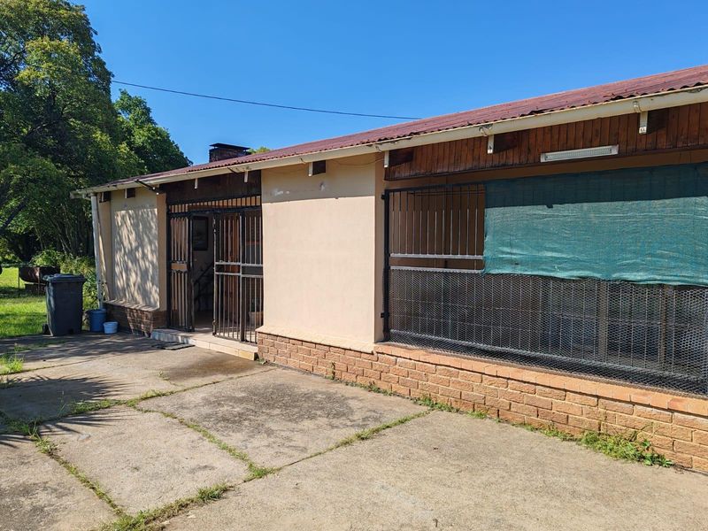 Rear exterior view of the farm building featuring a corrugated metal roof, brick base, and security-gated access to the patio area.