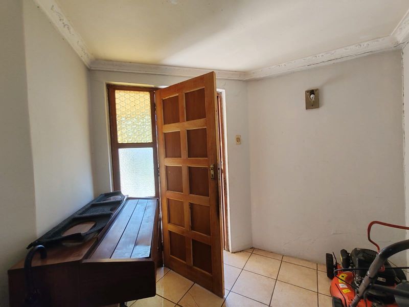 An entry area featuring tiled flooring, a timber panelled door, and decorative ceiling cornicing, requiring cosmetic updates to the wall finishes.