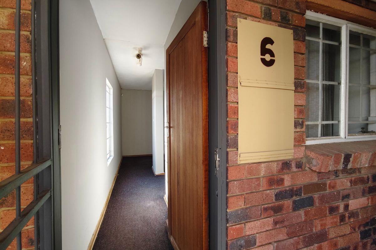 Entrance area featuring exposed brick exterior, a timber door, and a carpeted interior hallway.