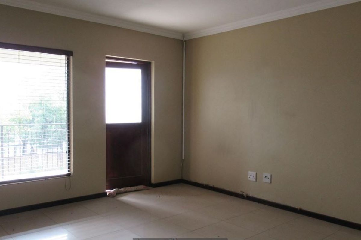 An empty bedroom featuring tiled flooring, neutral walls, and direct access to an outdoor area through a glass-paneled door.
