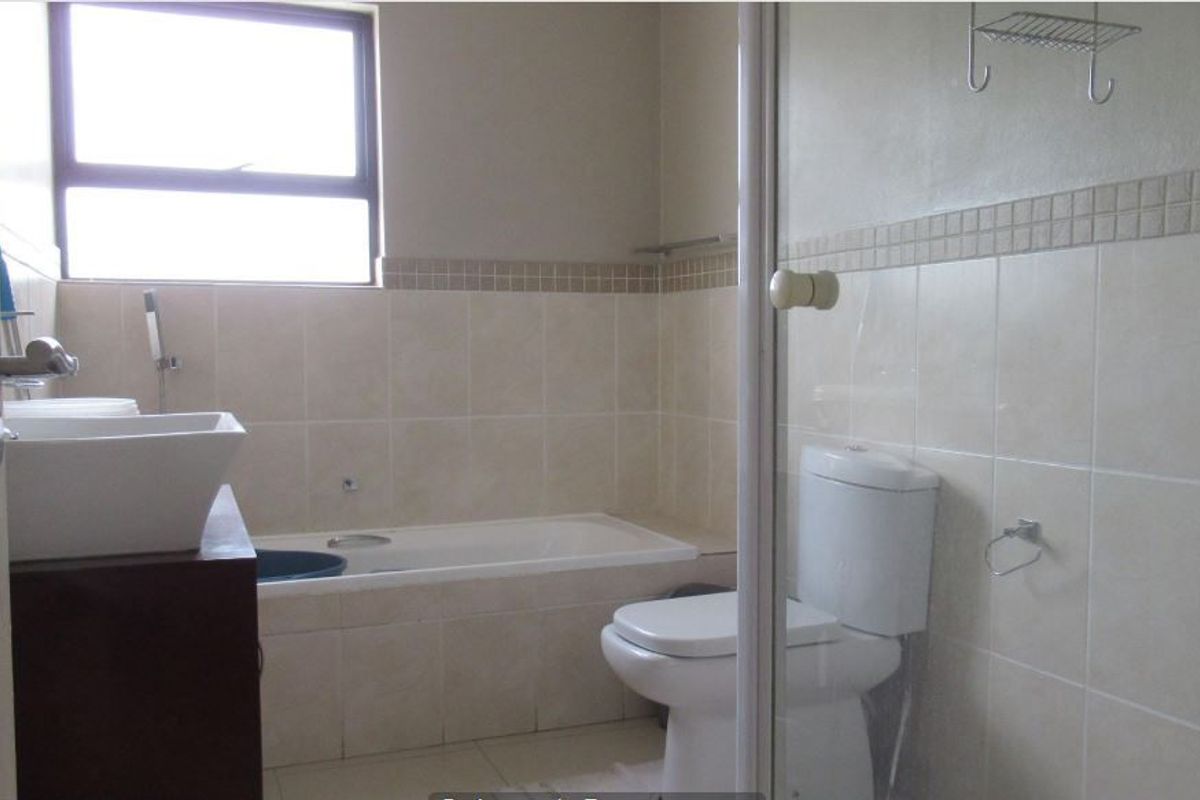A functional bathroom featuring a built-in bathtub, separate shower enclosure, toilet, and a modern vessel sink with tiled finishes throughout.