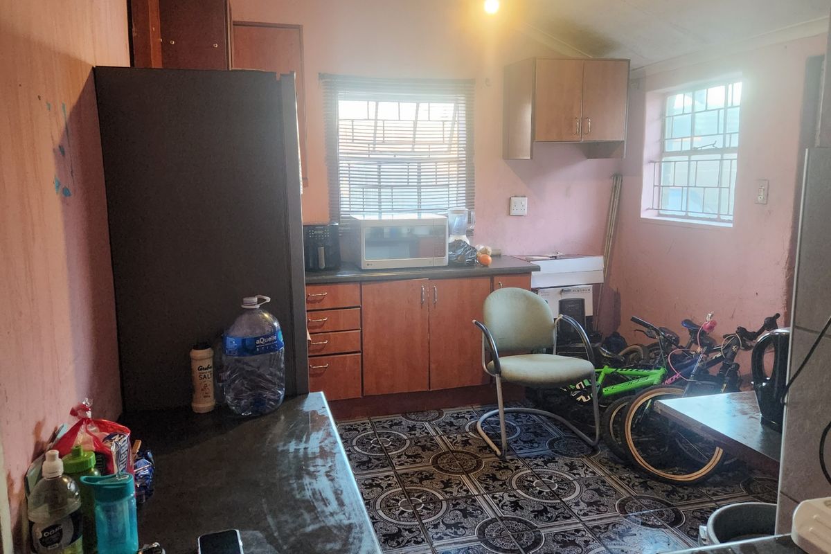 A dated kitchen featuring built-in cabinetry, laminate countertops, and patterned floor tiles, requiring cosmetic updates to modernize the space.