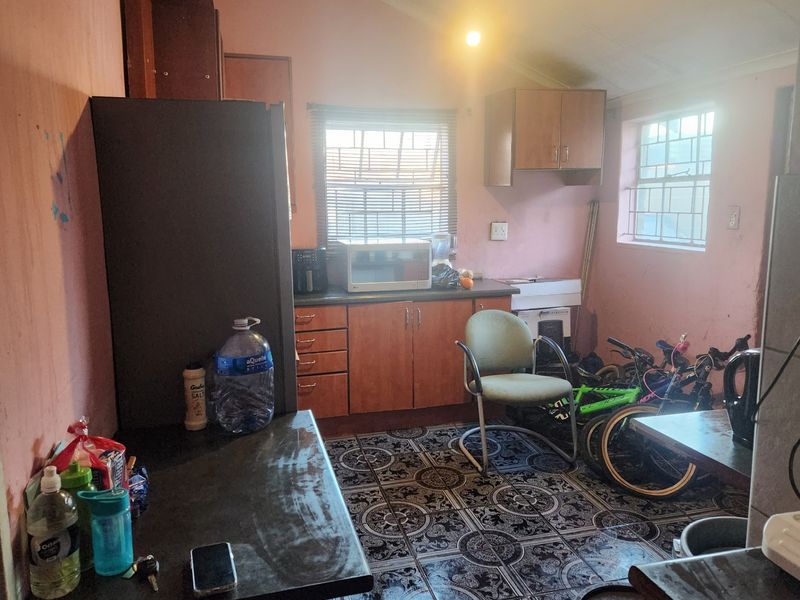 A dated kitchen featuring built-in cabinetry, laminate countertops, and patterned floor tiles, requiring cosmetic updates to modernize the space.
