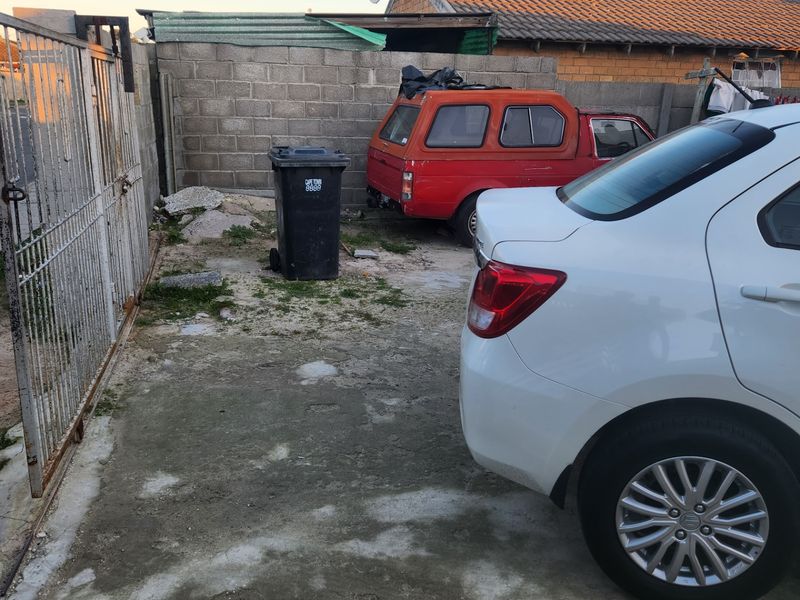 A concrete driveway area featuring a metal security gate and cinder block boundary walling.
